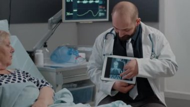 Hasta, muayene sonuçları için tabletteki röntgen taramasına bakıyor.
