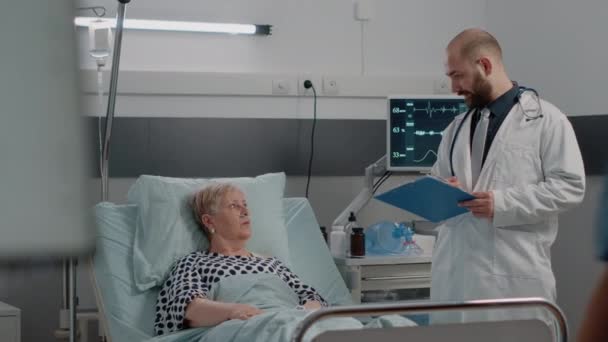 Equipe médica consulta mulher idosa com doença na cama — Vídeo de Stock