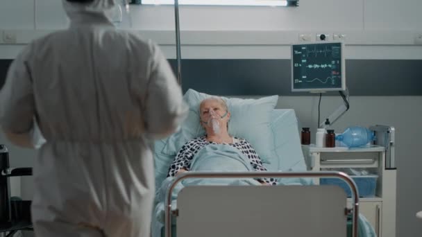 Orvos vegyvédelmi ruha csinál szűrővizsgálat látogatás idős nő — Stock videók
