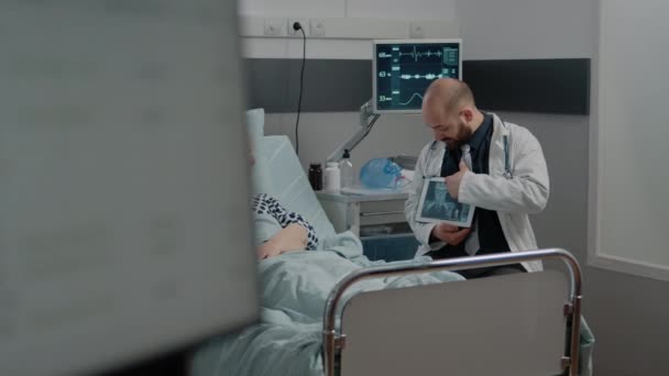 Médico apuntando a la pantalla de la tableta con radiografía para mujer enferma — Vídeos de Stock