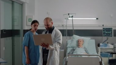 Doktor ve dizüstü bilgisayar danışmadan önce hemşireyle konuşuyor.