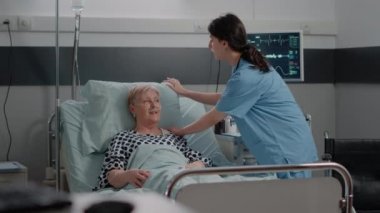 Hastane koğuşunda kıdemli bir hastayla konsültasyon yapan doktor.