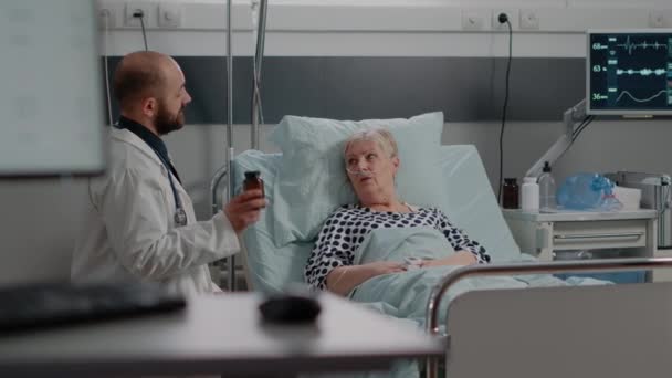 Doctor sosteniendo la botella de pastillas y explicando el tratamiento — Vídeos de Stock