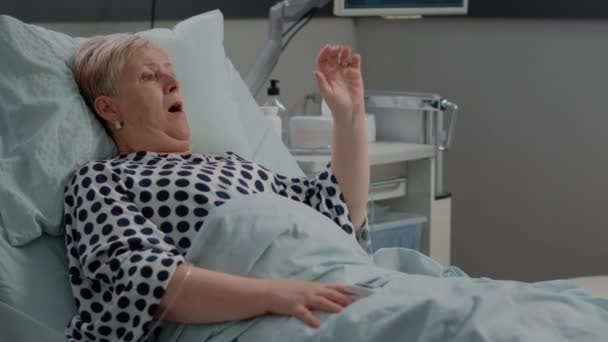 Starsza kobieta ciężko oddycha prosząc o pomoc w łóżku — Wideo stockowe