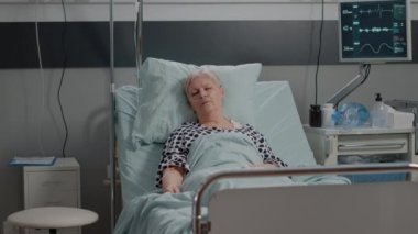 Serum serumlu yaşlı kadın hastane koğuşunda uyuyor.