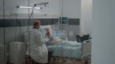 Doktor, yaşlı hasta için bir şişe ilaç veriyor.