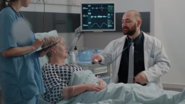 Doktor, hasta kadının nabız muayenesi için steteskop kullanıyor.
