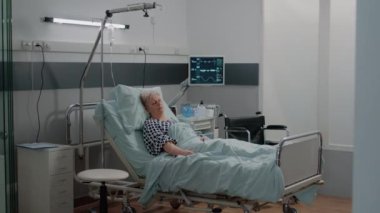 Tıbbi asistan emekli hastayı uyurken ziyaret ediyor.