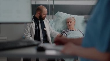 Doktor hastane koğuşunda hastalıklı emekli bir kadınla konuşuyor.
