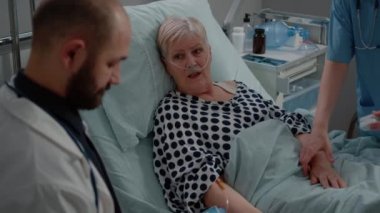 Yatakta yatan yaşlı hastayı kapat ve doktorla konuş.