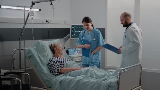 Equipo médico haciendo visita de chequeo para el paciente anciano con enfermedad — Vídeo de stock