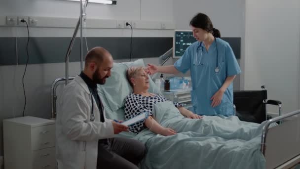 Лікар консультує хворого пацієнта в ліжку з носовою кисневою трубкою — стокове відео