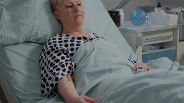 Portret van een gepensioneerde vrouw met een neuszuurstofbuis in bed — Stockvideo