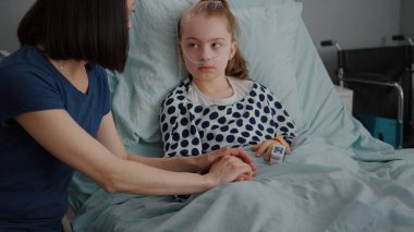 Yatakta dinlenen oksijen tüpü takan ve parmaklarında tıbbi oksimetrelerle hastanede yatan çocuk.