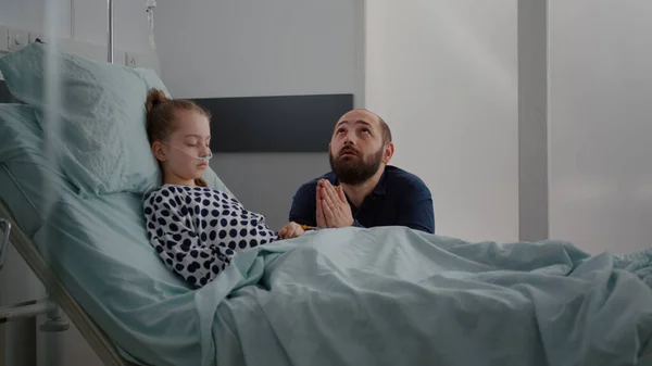 Niña enferma hija durmiendo después de la cirugía recuperación mientras padre preocupado rezando por la salud del niño —  Fotos de Stock
