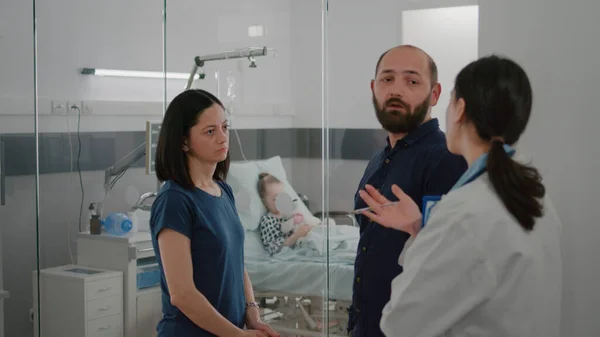 Padres preocupados discutiendo tratamiento de recuperación de la enfermedad con pediatra médico en la sala de hospital — Foto de Stock