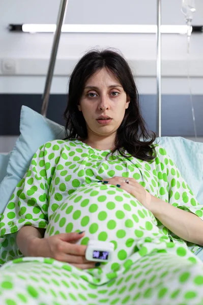 病院病棟のベッドに座っている疲れた妊婦の肖像 — ストック写真