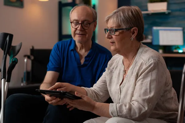 Verouderd paar op zoek naar moderne tablet in de woonkamer — Stockfoto