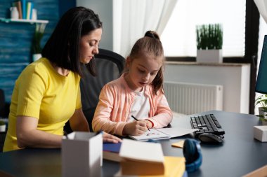 Okul ödevlerinde küçük kızına yardım eden bir ebeveyn.