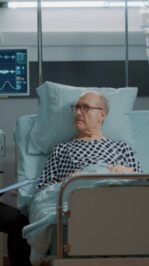 Afrikalı Amerikalı doktor yaşlı bir hastaya danışıyor.