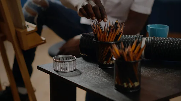 Крупним планом чорна рука використовує барвисті олівці на столі — стокове фото