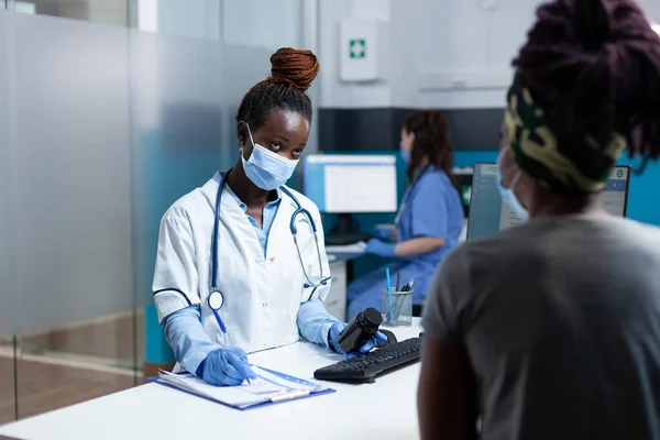 Médico afro-americano escrevendo tratamento de medicação na área de transferência — Fotografia de Stock