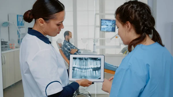 Стоматолог і медсестра аналізують рентгенографію зубів на планшеті — стокове фото