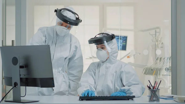 Equipe de odontologia de especialistas com ternos ppe usando computador — Fotografia de Stock