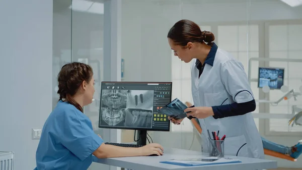 Dentist holding dentition x ray scan comparing to radiography — Stock Photo, Image