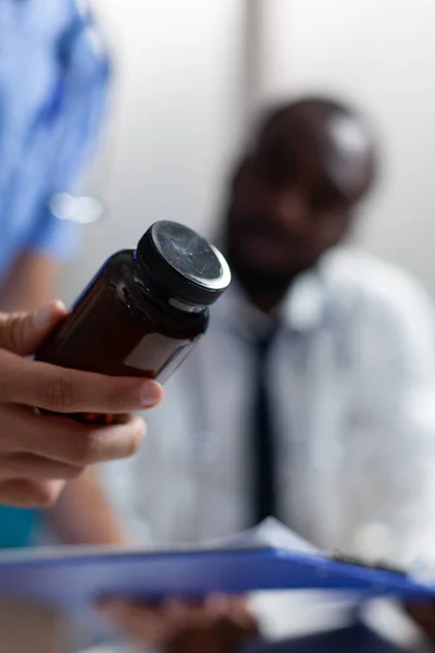Closeup of speicalist man nurse holding pills bottle analyzing sickness medicine prescription — Stock Photo, Image