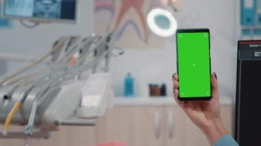 Yeşil ekranlı akıllı telefonu tutan dişçiyi kapat