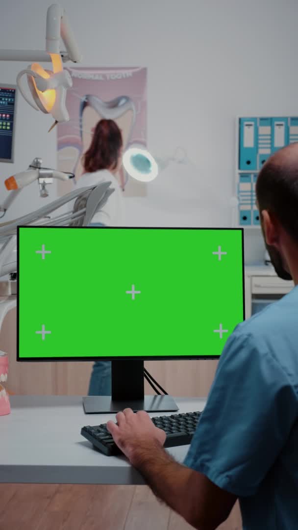 Vertical video: Assistant looking at horizontal green screen on computer — Stock Video