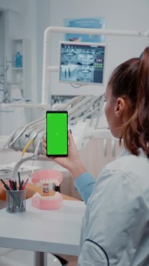 Dikey video: Kadın yeşil ekranlı cep telefonunu dikey olarak tutuyor