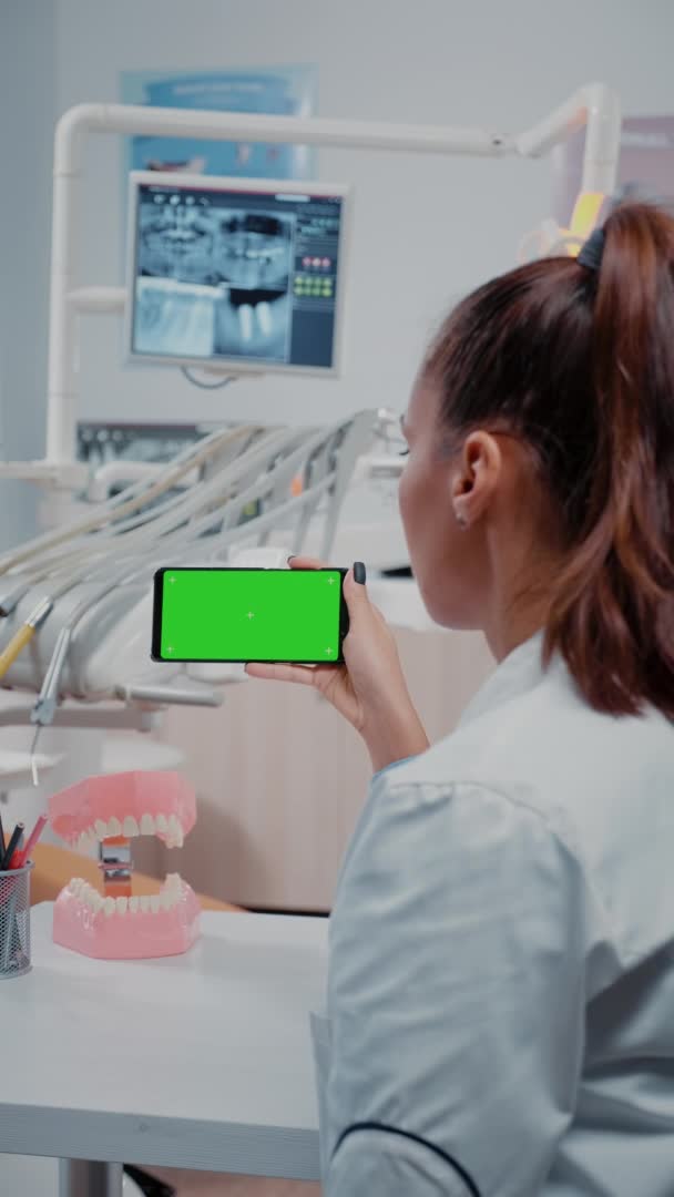 Vertical video: Specialist analyzing mobile phone with green screen — Stock Video