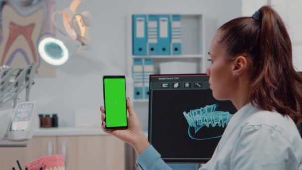 Крупный план ортодонта, держащего смартфон с зеленым экраном — стоковое видео