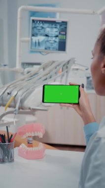 Dikey video: Dişçi yeşil ekranlı cep telefonuna bakıyor