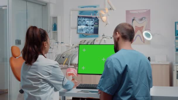 Kobieta dentysta i mężczyzna pracujący z zielonym ekranem na monitorze — Wideo stockowe