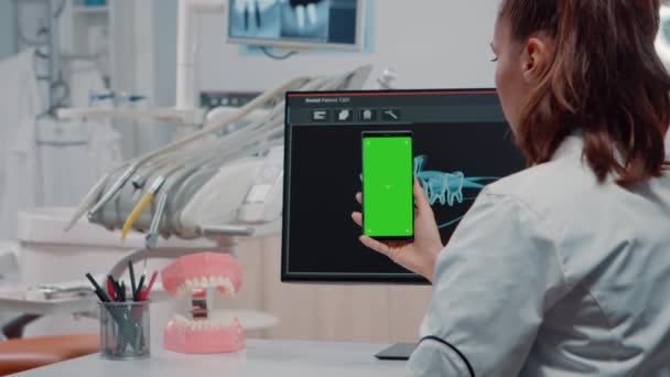 Стоматолог вертикально тримає смартфон із зеленим екраном — стокове відео
