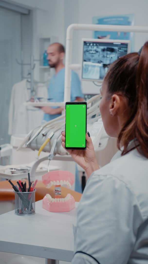 Vertical video: Woman vertically holding mobile phone with green screen — Stock Video