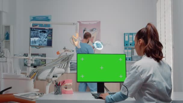 Tandarts met behulp van groen scherm op monitor en praten met man assistent — Stockvideo