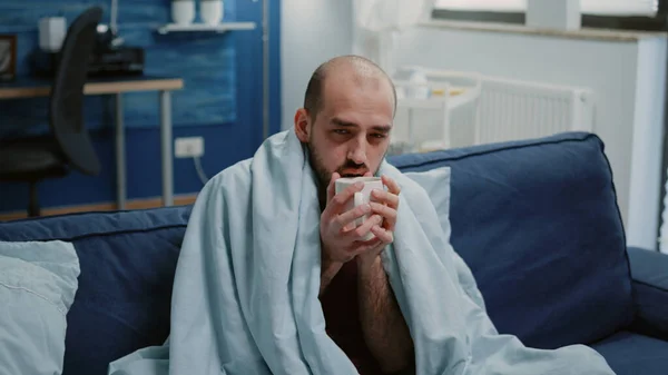 Homem doente segurando xícara de chá e olhando para a câmera — Fotografia de Stock