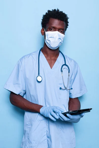 Nurse holding tablet terwijl het kijken naar de camera over geïsoleerde achtergrond — Stockfoto