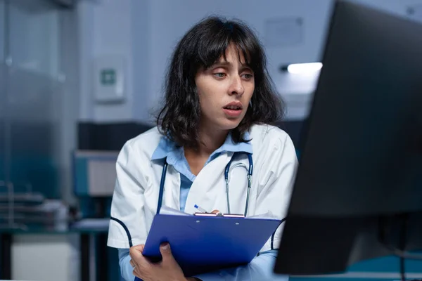Professional medic looking at computer screen and medical files — Stock Photo, Image