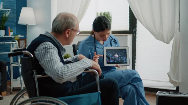 Uomo disabile anziano guardando l'animazione del virus su tablet — Foto Stock