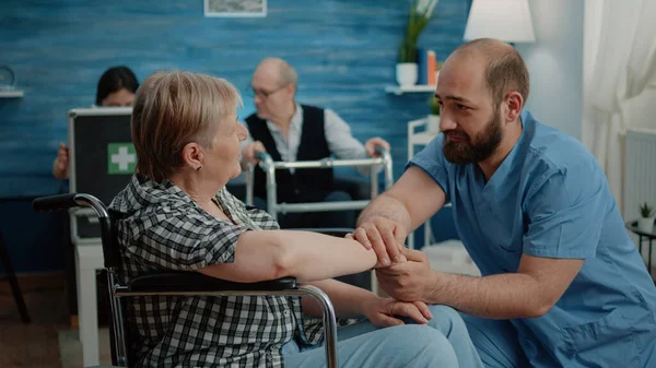 Чоловік медсестра втішає старшу жінку з хронічними проблемами — стокове фото