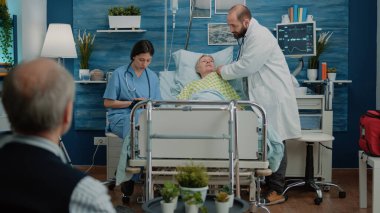 Doktor, hastane yatağında steteskop kullanıyor.