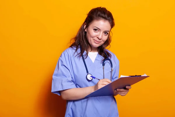 Enfermera con uniforme escrito en papeles portapapeles — Foto de Stock