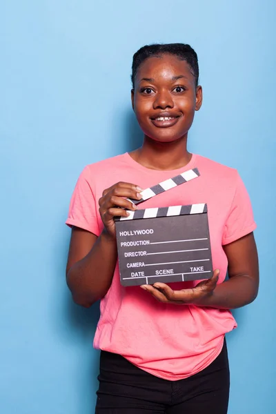 Portrét usmívající se africké americké mladé ženy držící filmografii clapboard — Stock fotografie