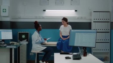 Yatakta genç bir hasta yıllık sağlık kontrolü için doktorla konuşuyor.