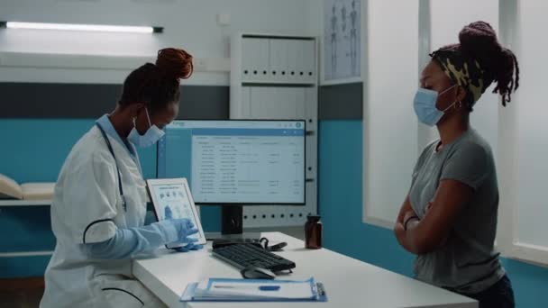 Dokter toont botten anatomie op tablet tijdens het dragen van gezichtsmasker — Stockvideo